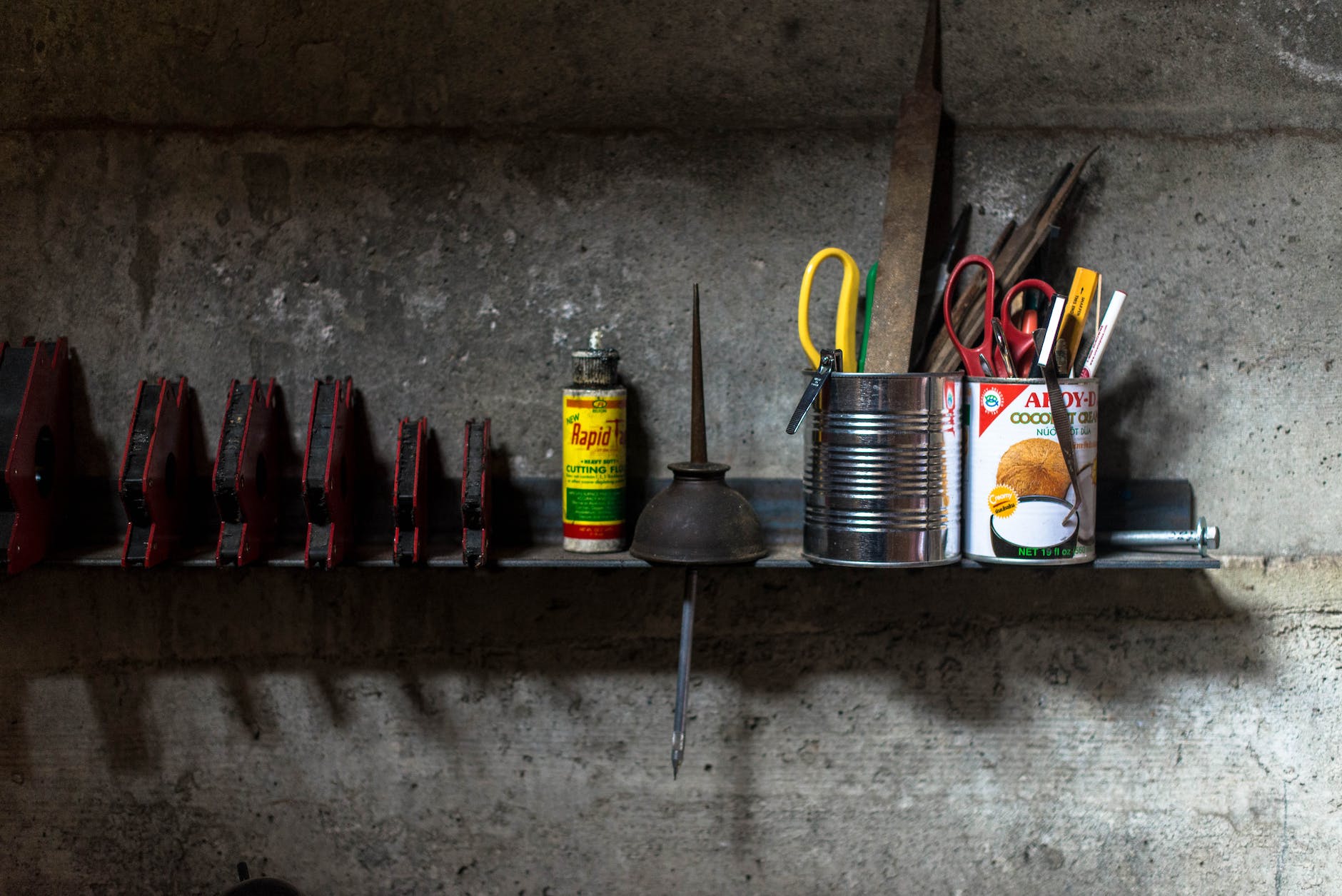 assorted color scissors and pens in tin cans on brown wooden wall shelf