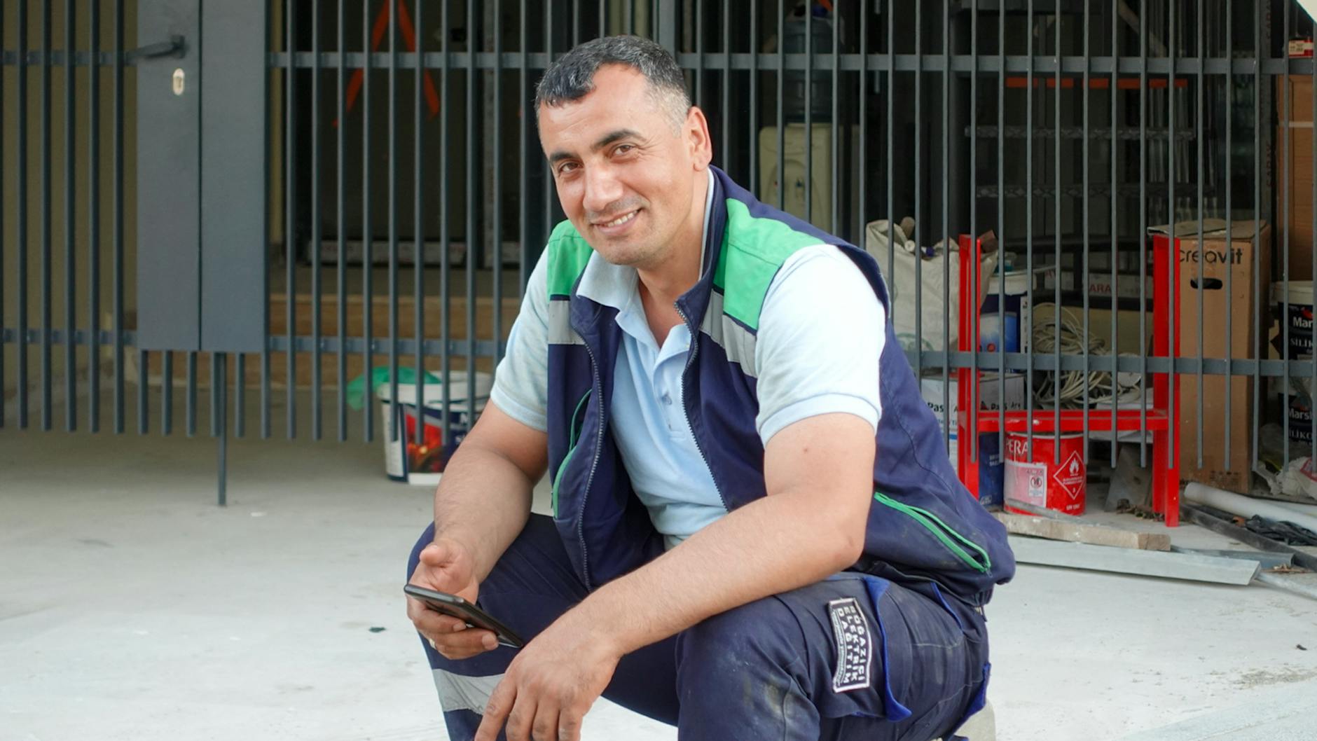 smiling construction worker using smartphone outdoors