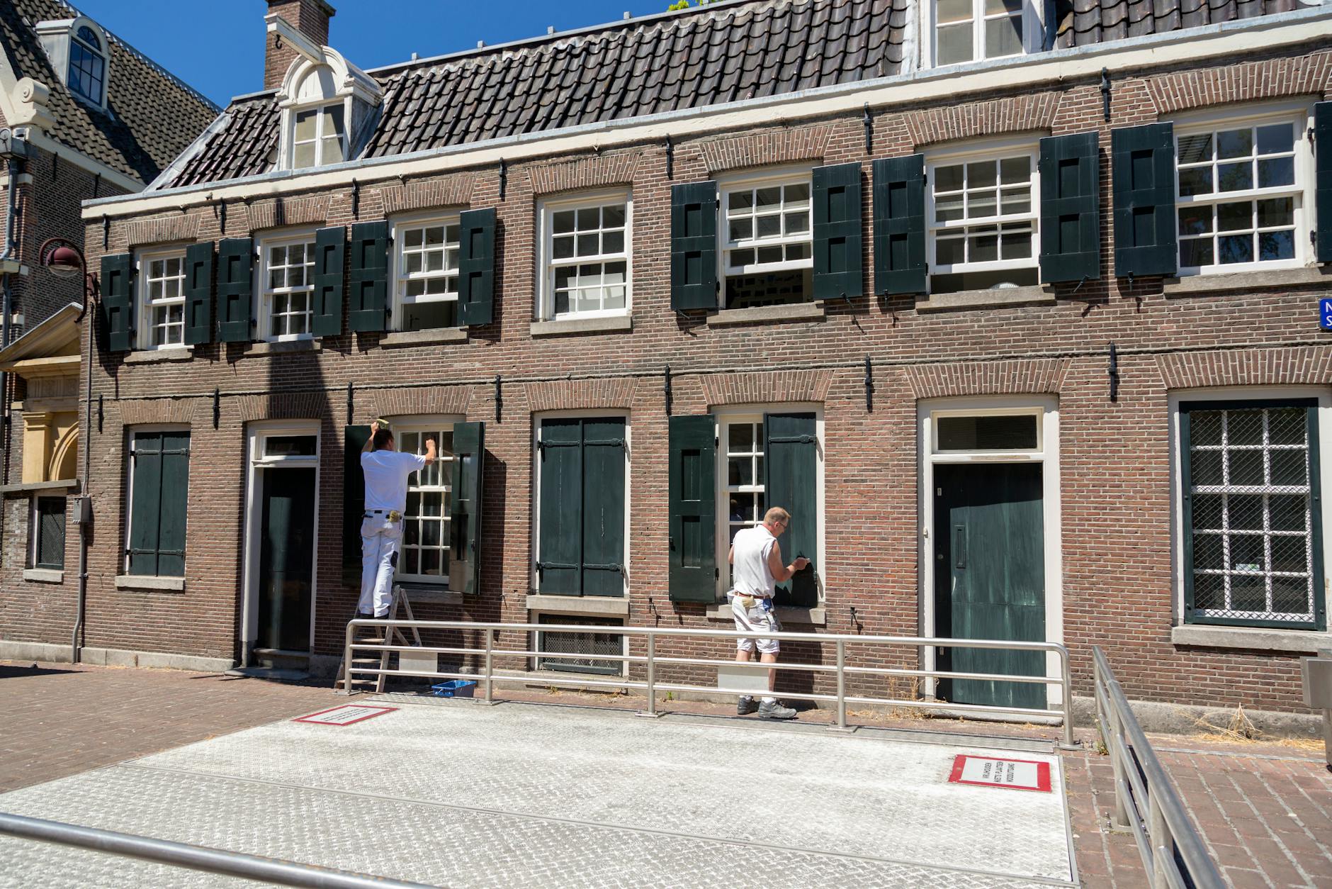 painters working on dutch brick house exterior