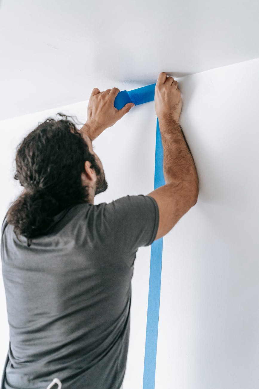 man putting adhesive tape on wall