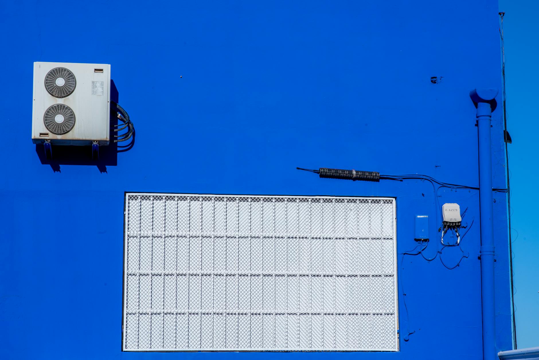 air conditioner on vibrant blue wall exterior